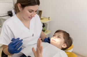 Diş hekimi çocuk hastanın süt dişini kontrol ediyor